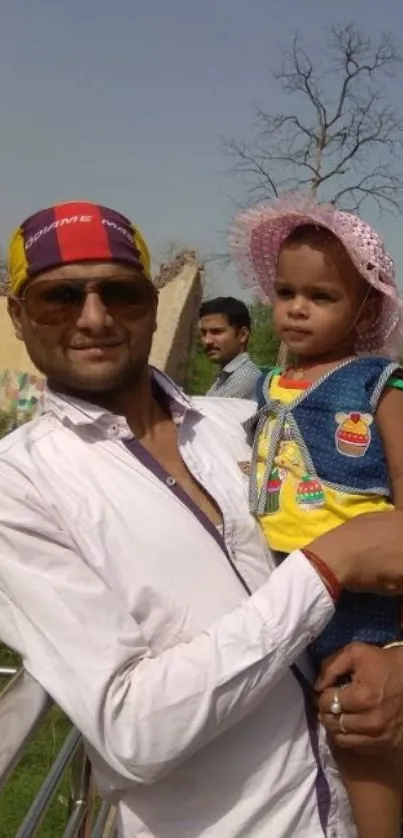 Father holding child outdoors on a sunny day.