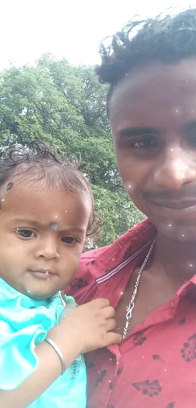 Father holding child outdoors with lush green background.