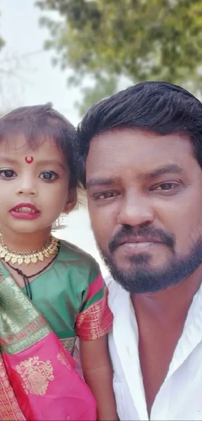 Father and daughter smiling outdoors in traditional attire.