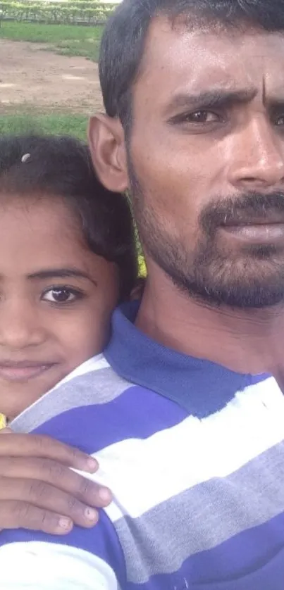 Father and daughter smile warmly in a lush green park setting.