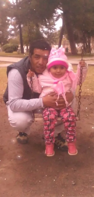 Father and daughter on swing in park.
