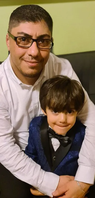 Father hugging son, both in formal attire, with a warm smile.