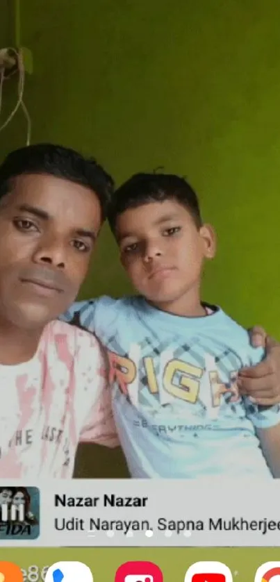 Father and son pose against a lime green wall.