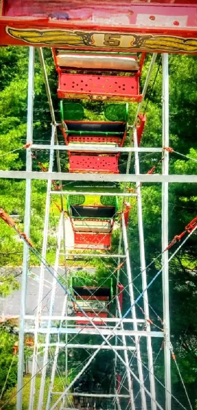 Aerial view of red Ferris wheel over lush green forest.