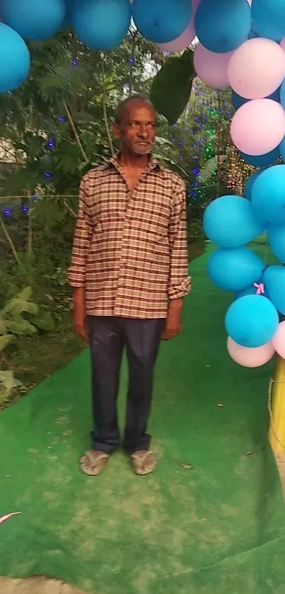 Man standing under colorful balloon arch outdoors.