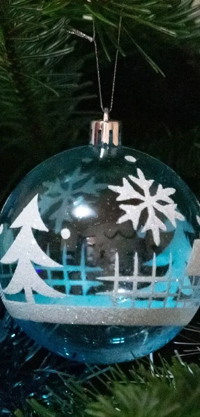 Festive blue Christmas ornament with snowflake and tree patterns on a green tree.