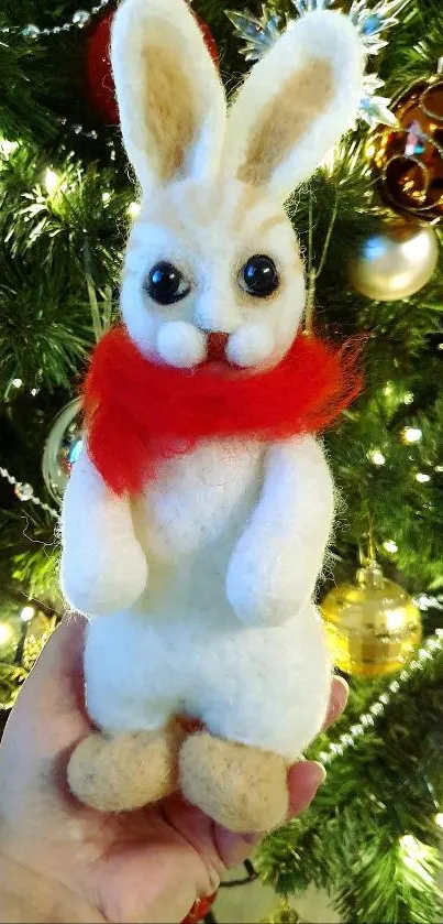 Felt bunny with red scarf in front of Christmas tree.