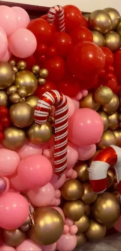 Festive candy-themed balloon wall with pink, red, and gold colors.