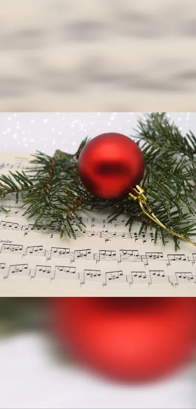 Red Christmas ornament on music sheet with evergreen branches.