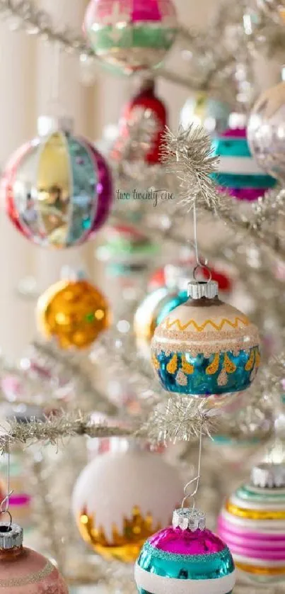 Colorful Christmas ornaments on a silver tree.