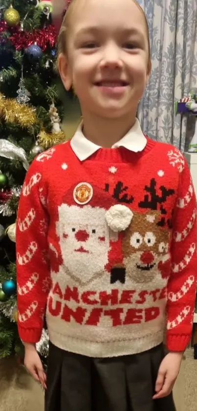 Child in a red Christmas sweater with festive background.