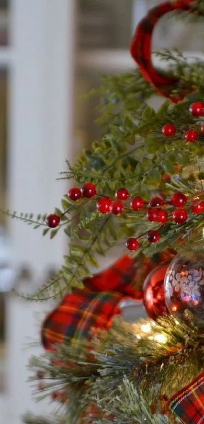 Christmas tree with red berries and plaid ribbon decorations.