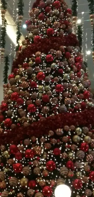 Tall Christmas tree with red ornaments and festive lights.