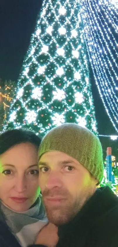 Couple in front of a festive, lit Christmas tree.