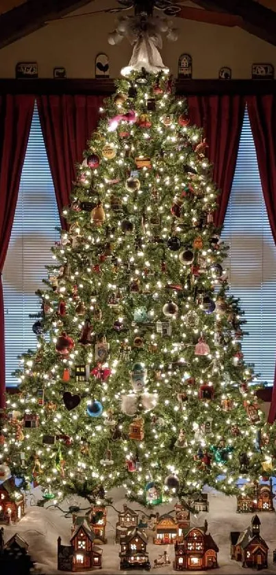 Decorated Christmas tree with lights and village houses under warm lighting.