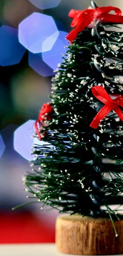 Mini Christmas tree with bokeh lights and red ribbons.