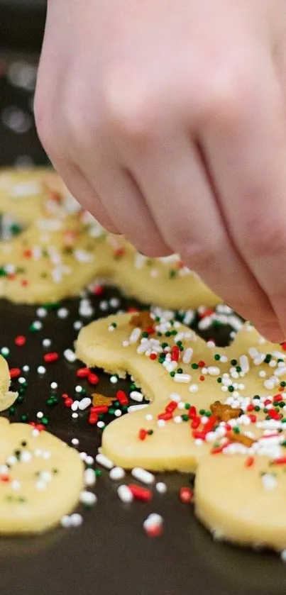 Hand decorating festive cookies with sprinkles on dough.