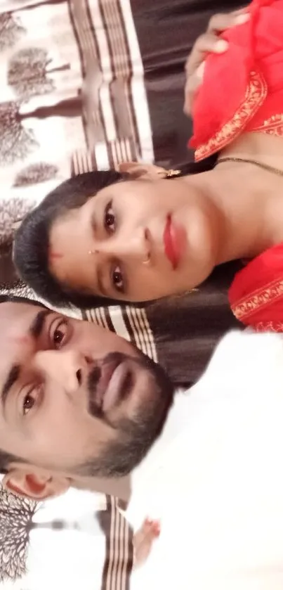 Festive couple posing in traditional attire against a decorative background.