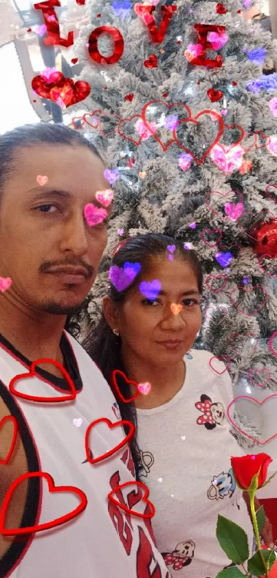 Couple in front of Christmas tree with love decorations and red accents.