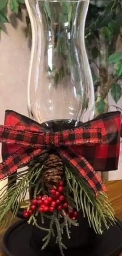 Festive glass candle holders with plaid ribbons and winter decorations on a wooden table.