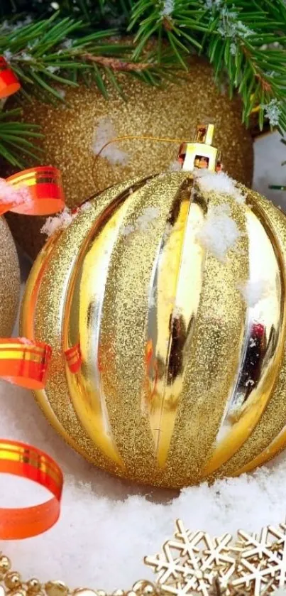 Golden Christmas ornament with ribbon on snow and fir branches.