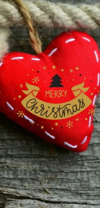 Red fabric heart with Merry Christmas design on rustic wood.