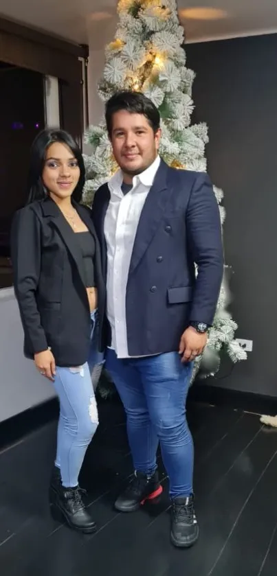 Couple by Christmas tree in elegant attire.