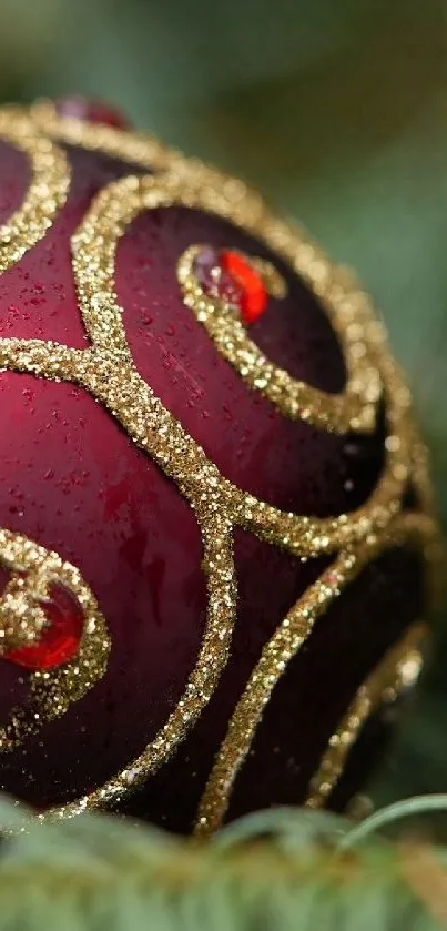 Red Christmas ornament with golden swirls on pine branches.
