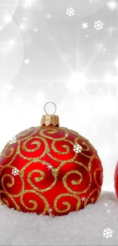 Festive red Christmas ornaments on snow with sparkling lights.