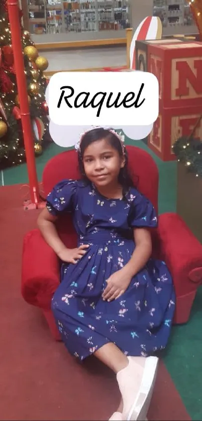 Girl in blue dress sitting in festive holiday setting.