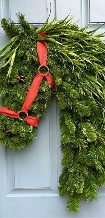 Horse-shaped wreath with green foliage and red ribbons on a door.