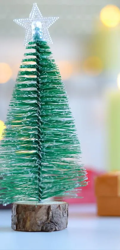 Green mini Christmas tree with glowing lights and gift boxes in the background.