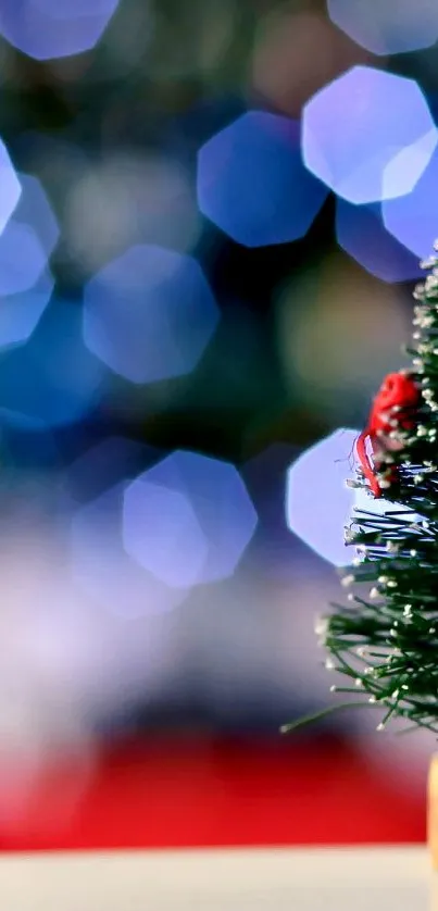 Miniature Christmas tree with red decorations and bokeh lights in the background.