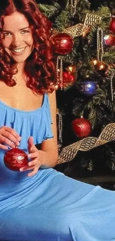 Woman in blue dress with festive Christmas tree background.