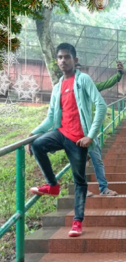 Man on stairs with festive decor and green background.