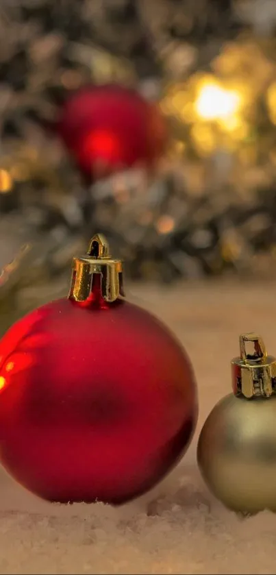 Mobile wallpaper with red and gold Christmas ornaments on snow.