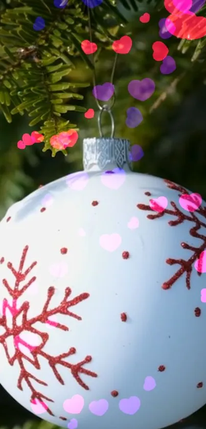 Christmas ornament with snowflake on evergreen branch, colorful hearts.