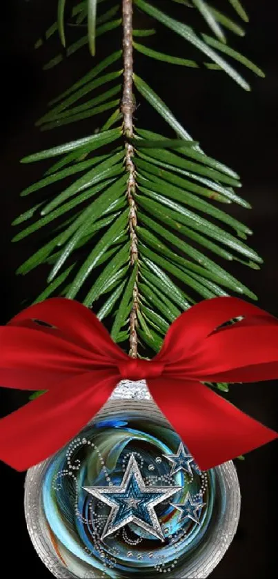 Festive ornament with red ribbon on pine branch against black background.