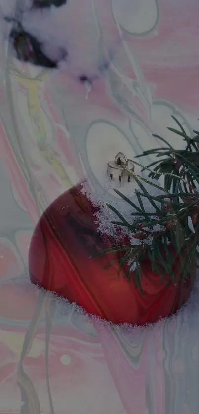 Red ornament and pine branch in snowy setting.