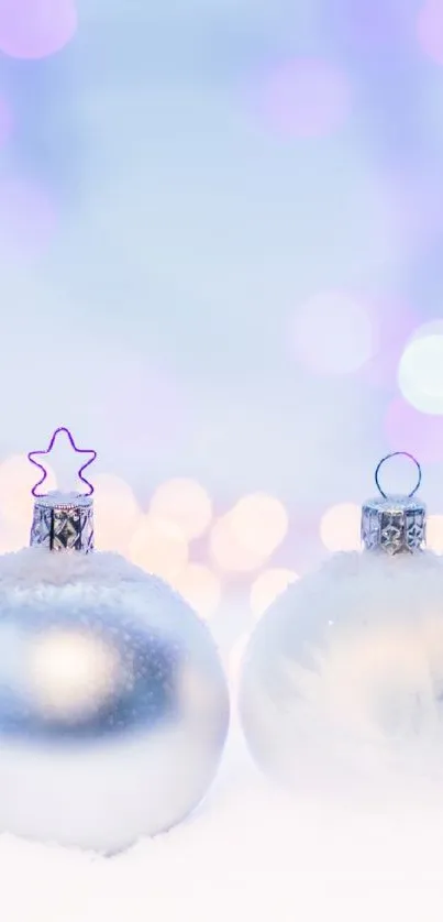 Silver ornaments in snow with soft bokeh lights, creating a festive holiday scene.