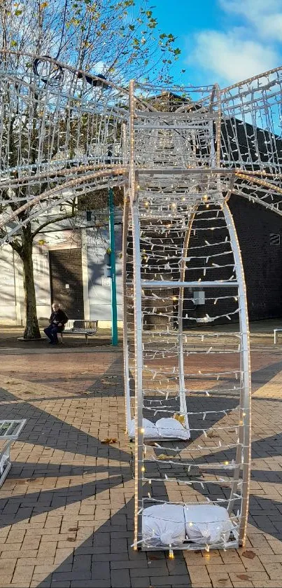 Outdoor light sculpture in a town square under a blue sky.