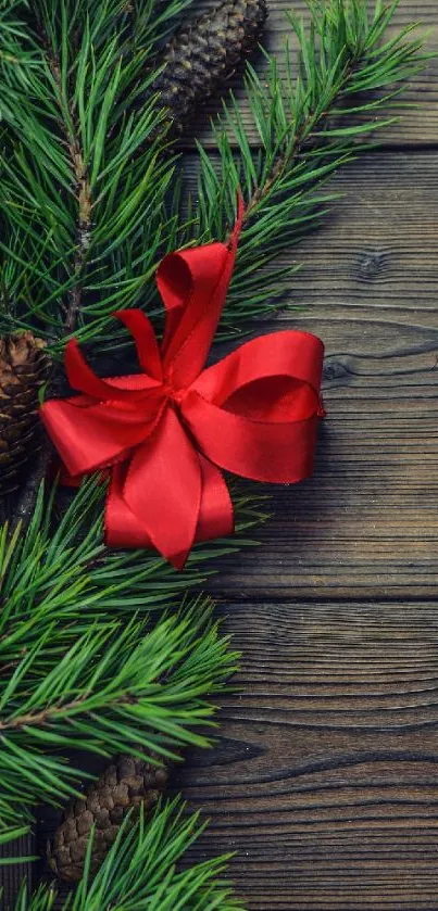 Festive pine branches with a red ribbon on wooden background.