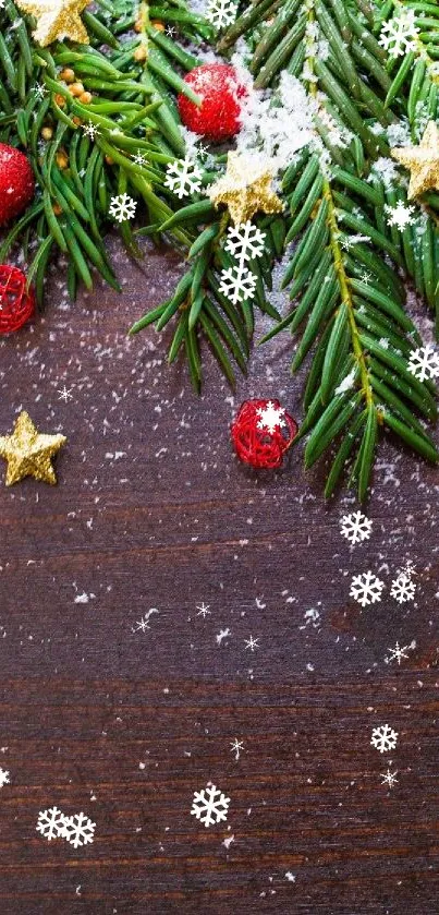 Festive wallpaper with pine branches and red ornaments on wooden background.