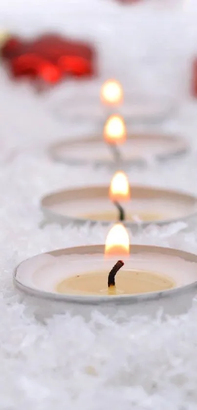 Red ornaments and candles on snowy background for holiday wallpaper.