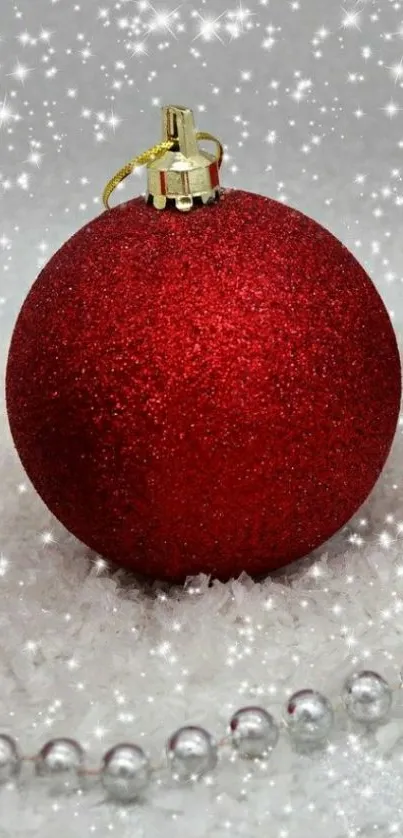 Festive red Christmas ornaments on snow with sparkling details.