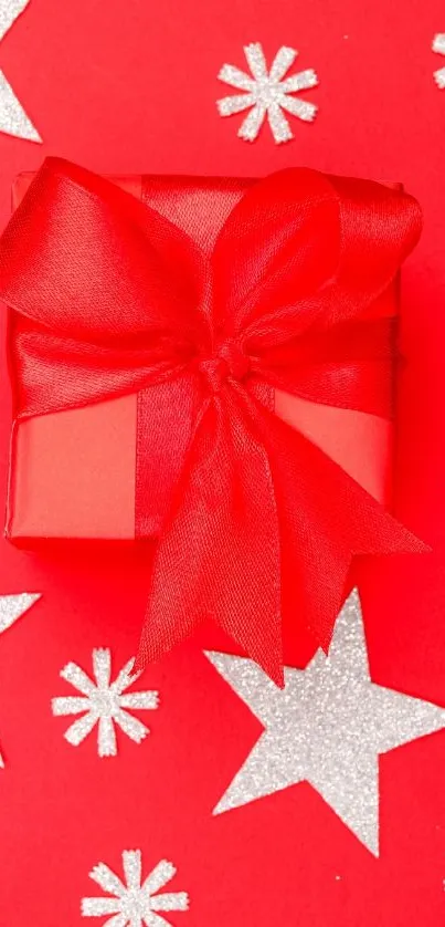 Festive red gift box with ribbon and stars in background.