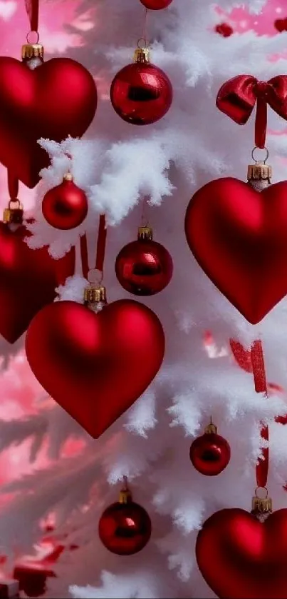 Red heart ornaments on a white Christmas tree with a pink background.