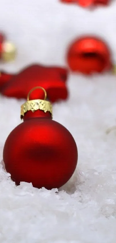 Festive wallpaper with red ornaments and glowing candles on snow.