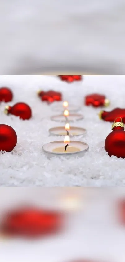 Festive red ornaments and candles on snowy background.