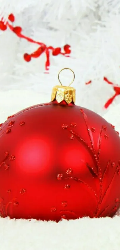 Red Christmas ornament against snowy white background.